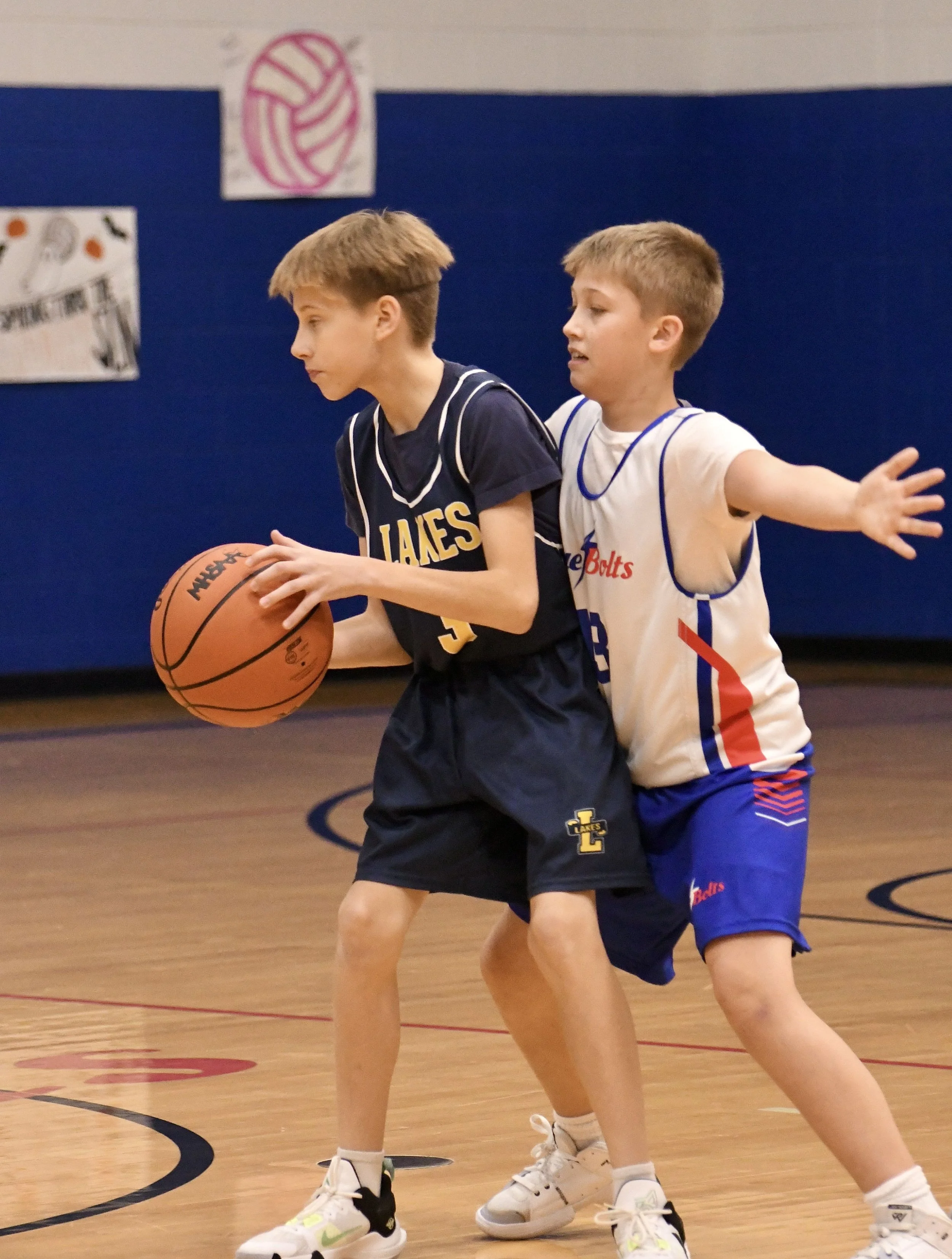 Junior high boy playing aggressive defense, with his chest against the opponent and hands wide out.
