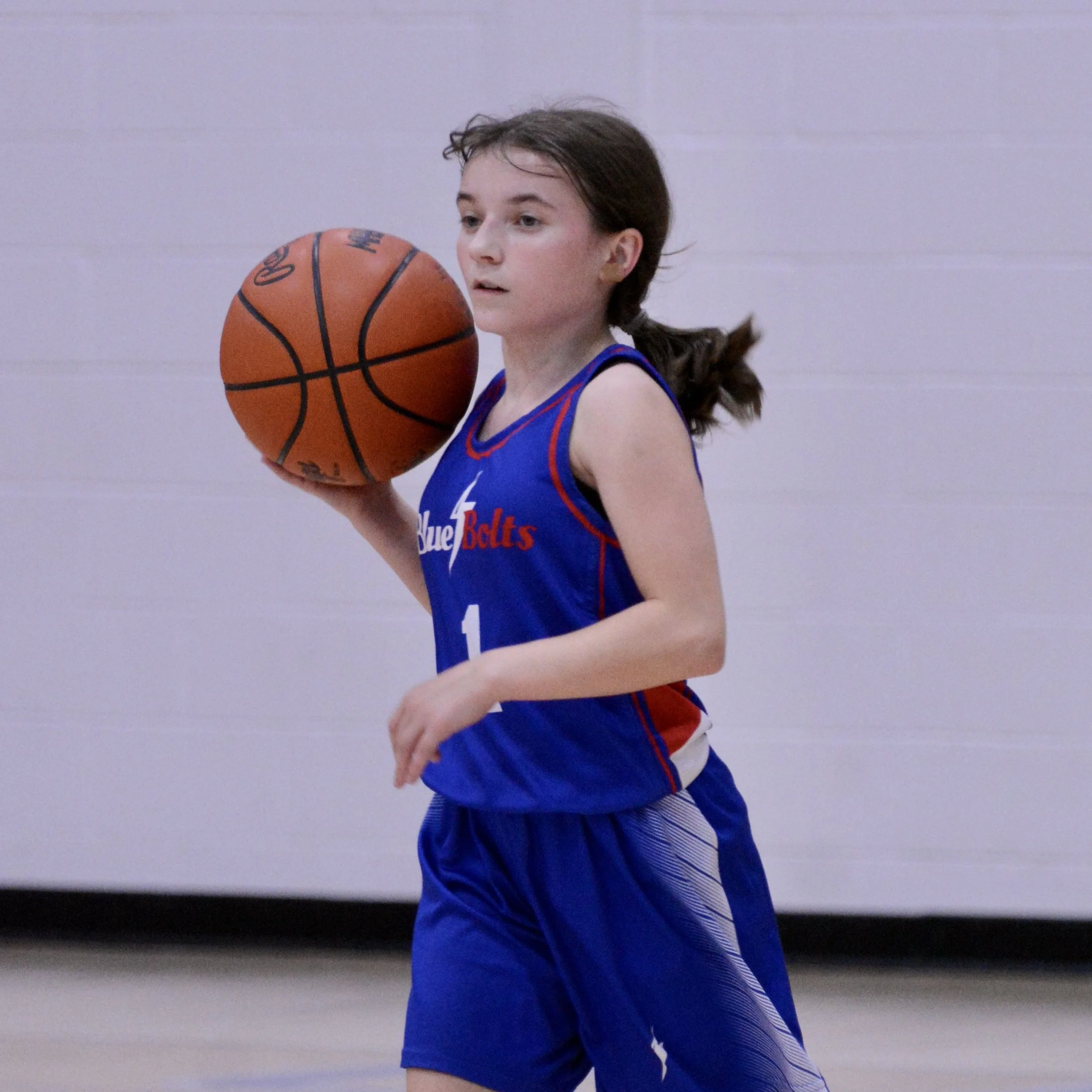 Junior high girl with high dribble while scouting the defense in front of her.