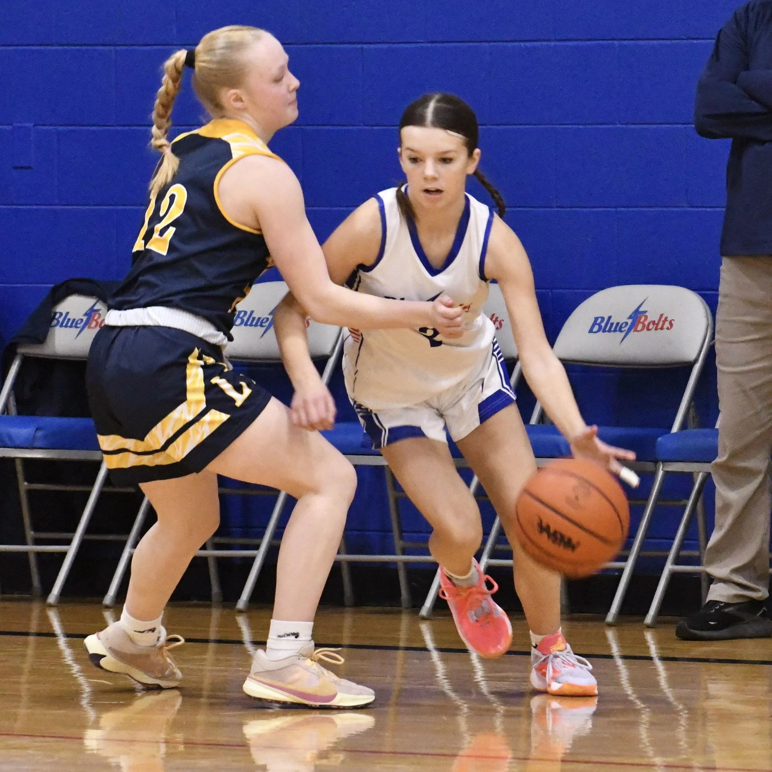 Junior varsity player, making a move to drive past her defender near the 3-point line.
