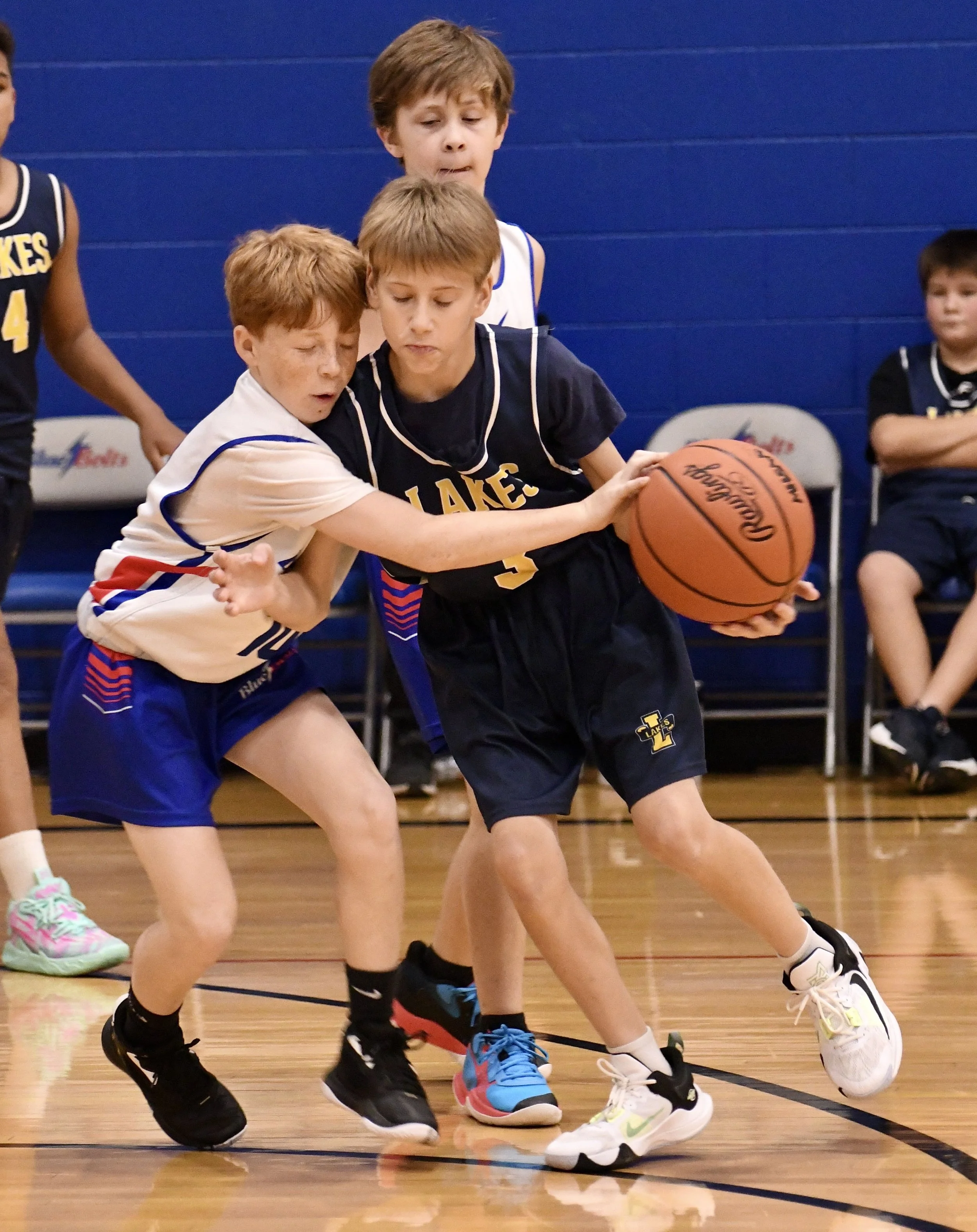 Junior high boy committing an obvious reaching foul against an opponent who is dribbling a basketball.