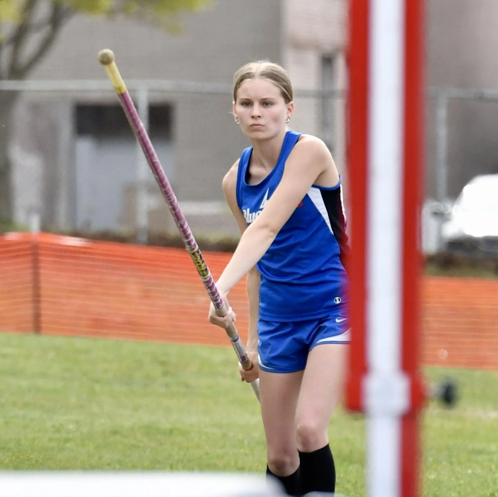 A junior high female holding her pole vault  in preparation for her attempted vault. 