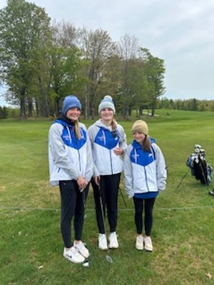 Three female golf members in Dollar Bay white and blue jackets posing on the fairway.