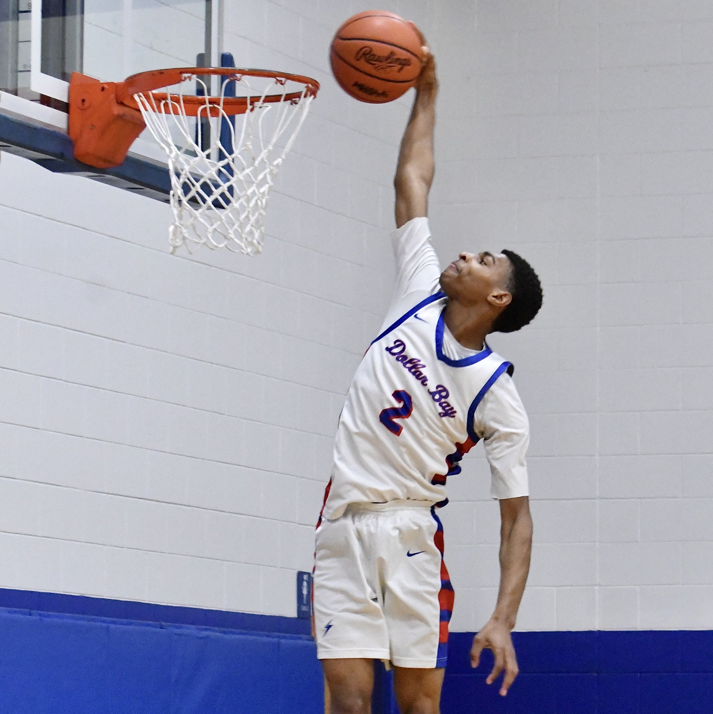 Tall lanky varsity boy, rising to dunk the ball, with no one else around.