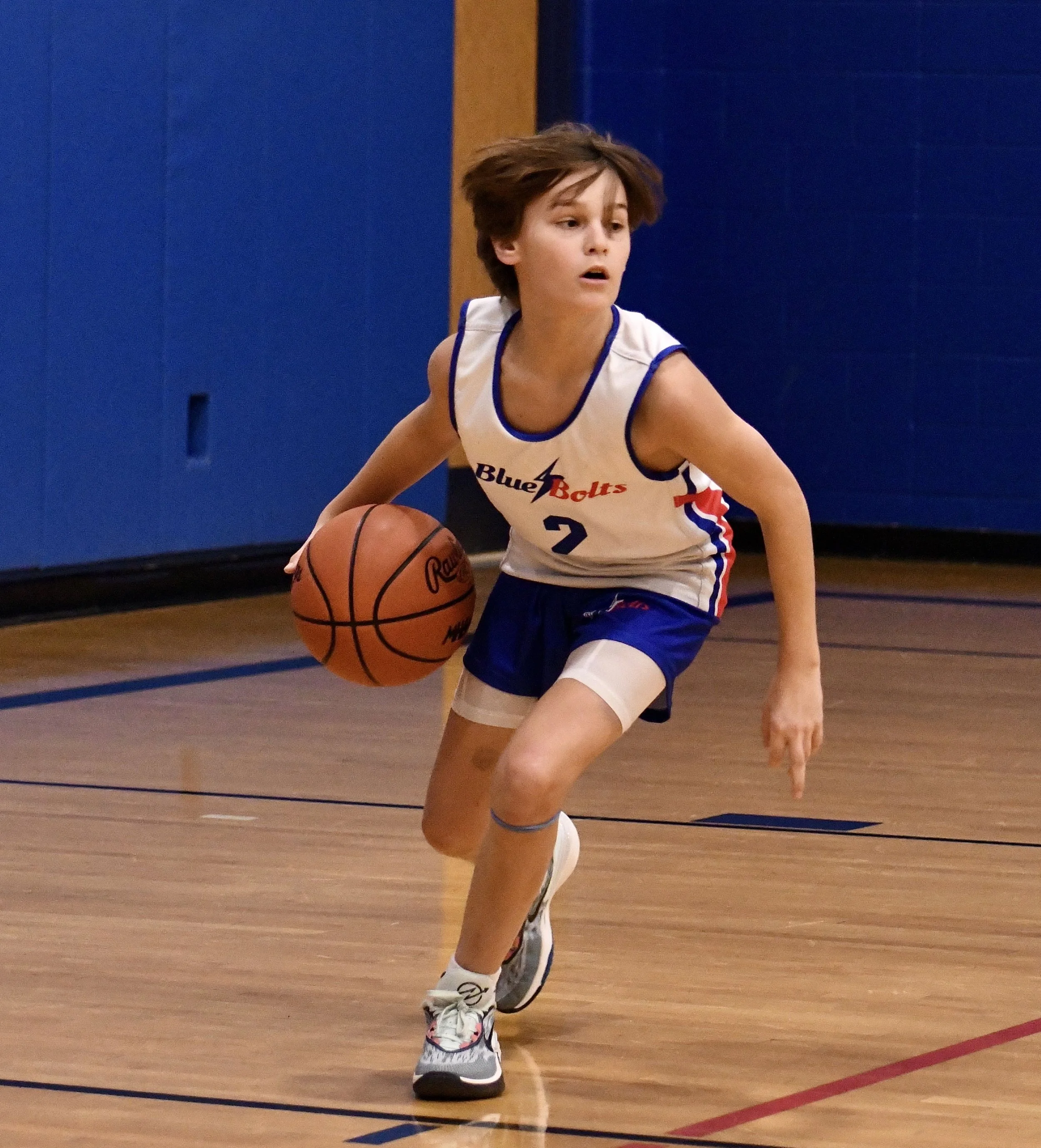 Junior high boy who is dribbling a basketball from deep in the backcourt.
