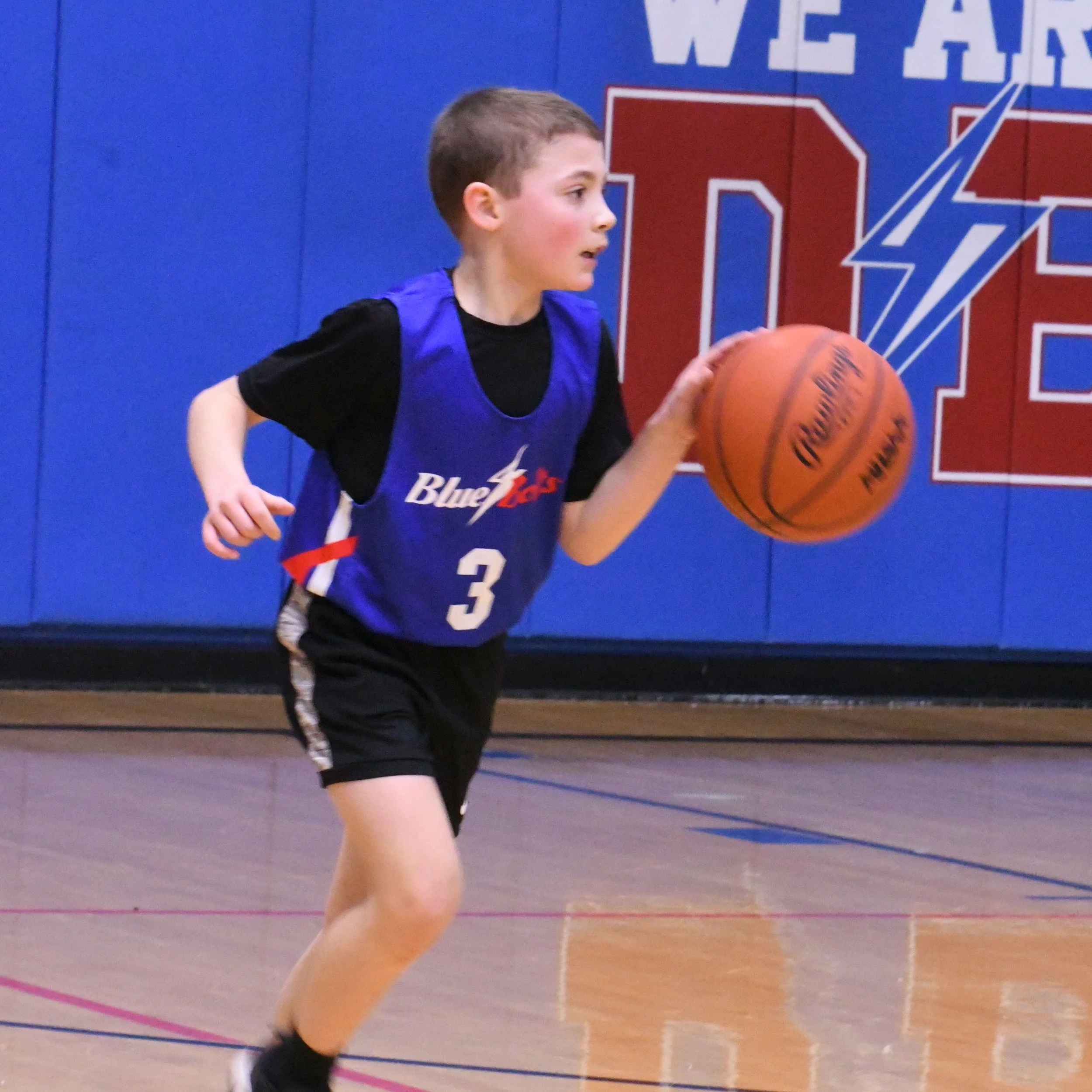 Elementary boy dribbling a basketball.