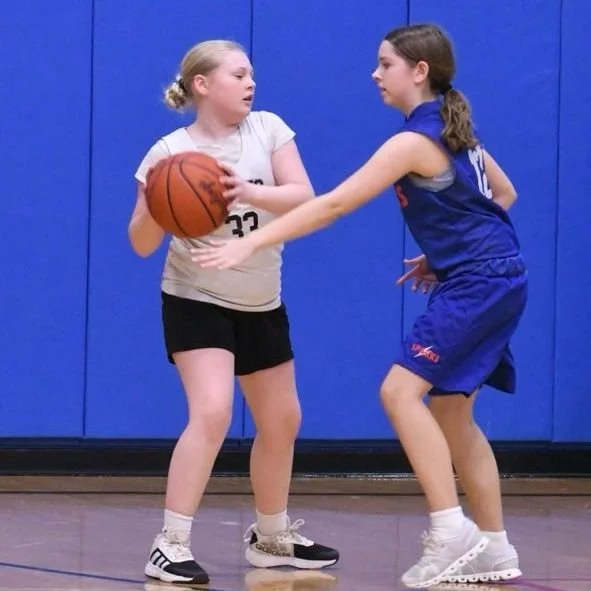 Elementary girl playing tough defense against an opponent.