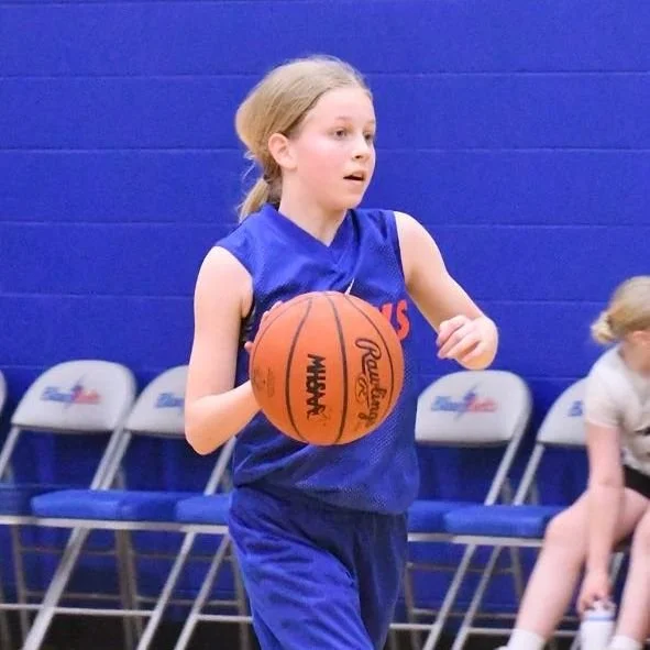 Elementary girl dribbling a basketball.