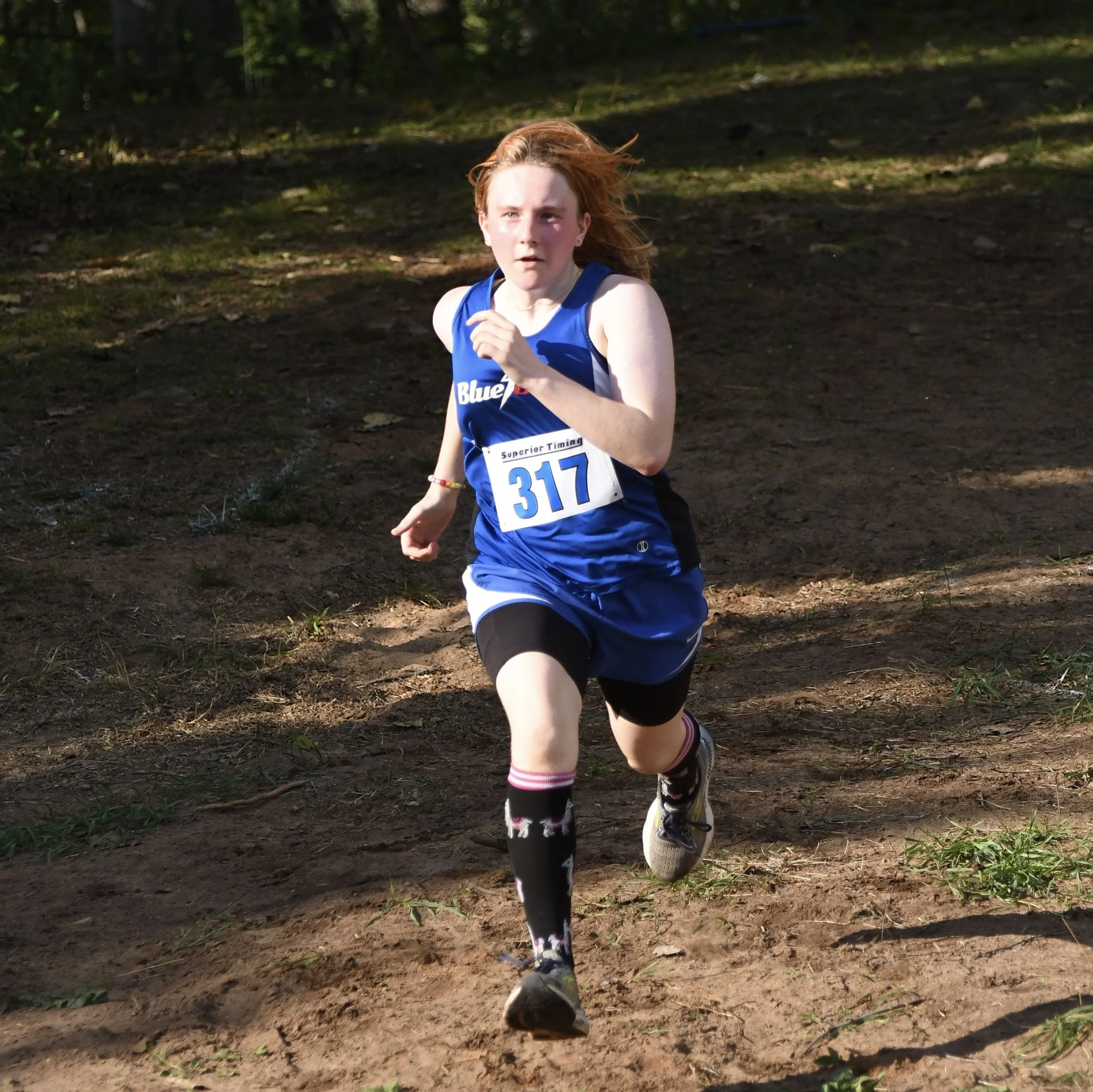 A varsity female Dollar Bay runner, sprinting towards the finish line.