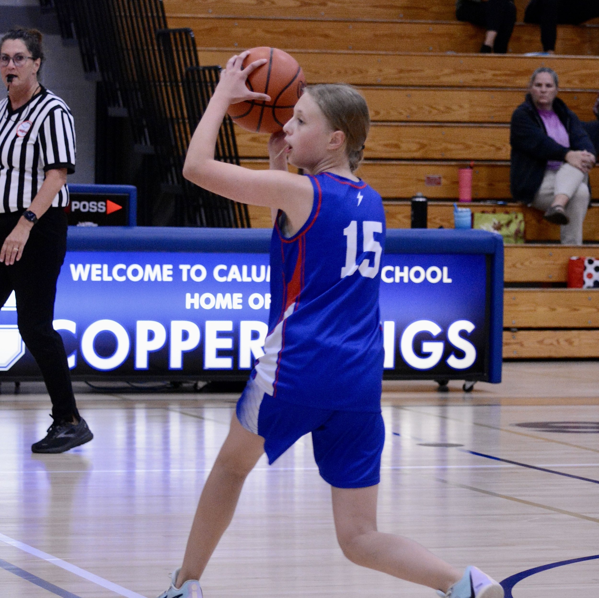Junior high girl stepping in to a two handed overhead pass, near the top of the 3 point line