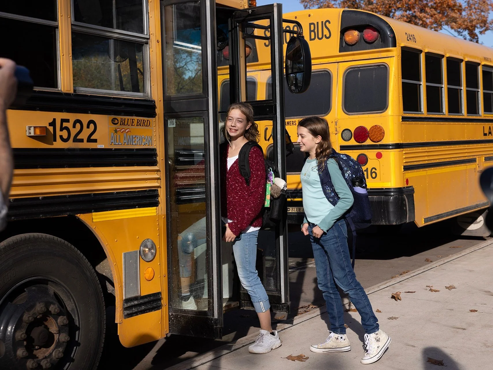 Two junior high students stepping on to a bus.
