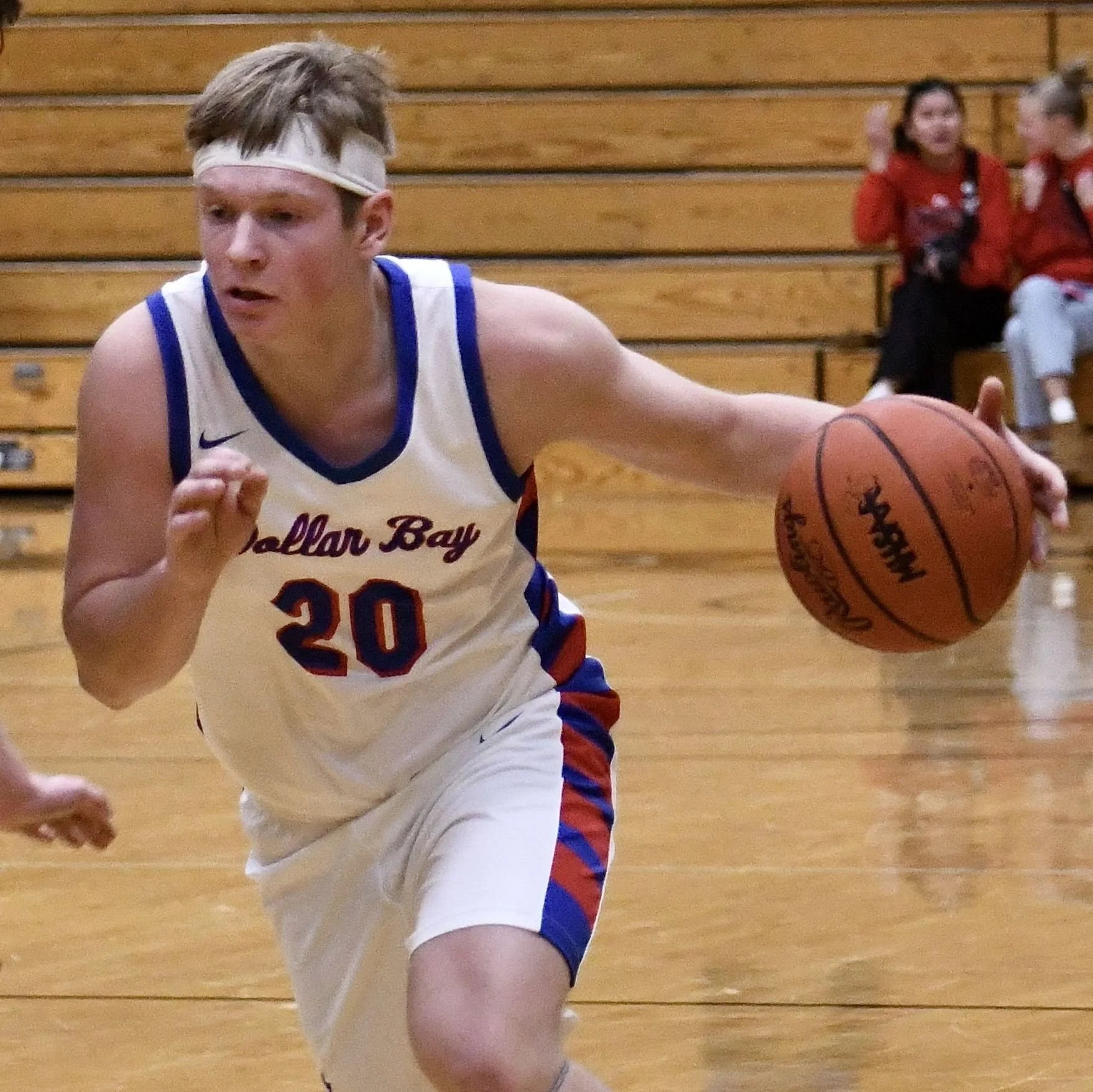 Varsity boy making a slashing drive around the defender while dribbling the ball.