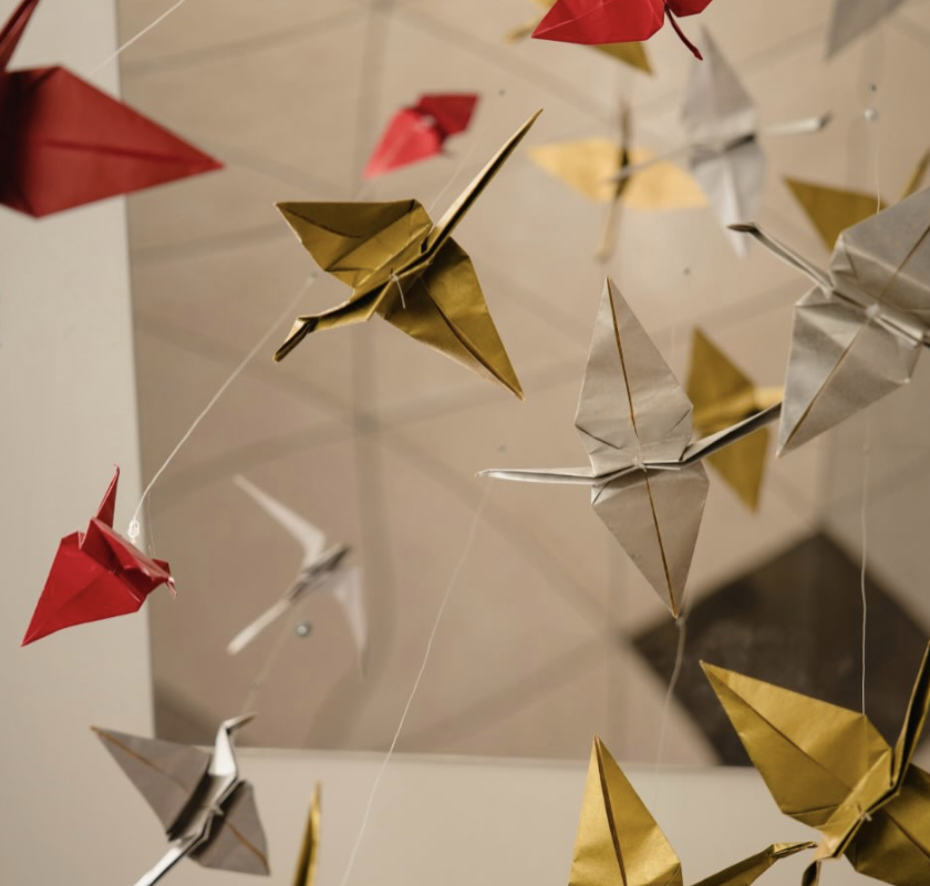Decorative paper butterflies and origami birds hanging on transparent strings.