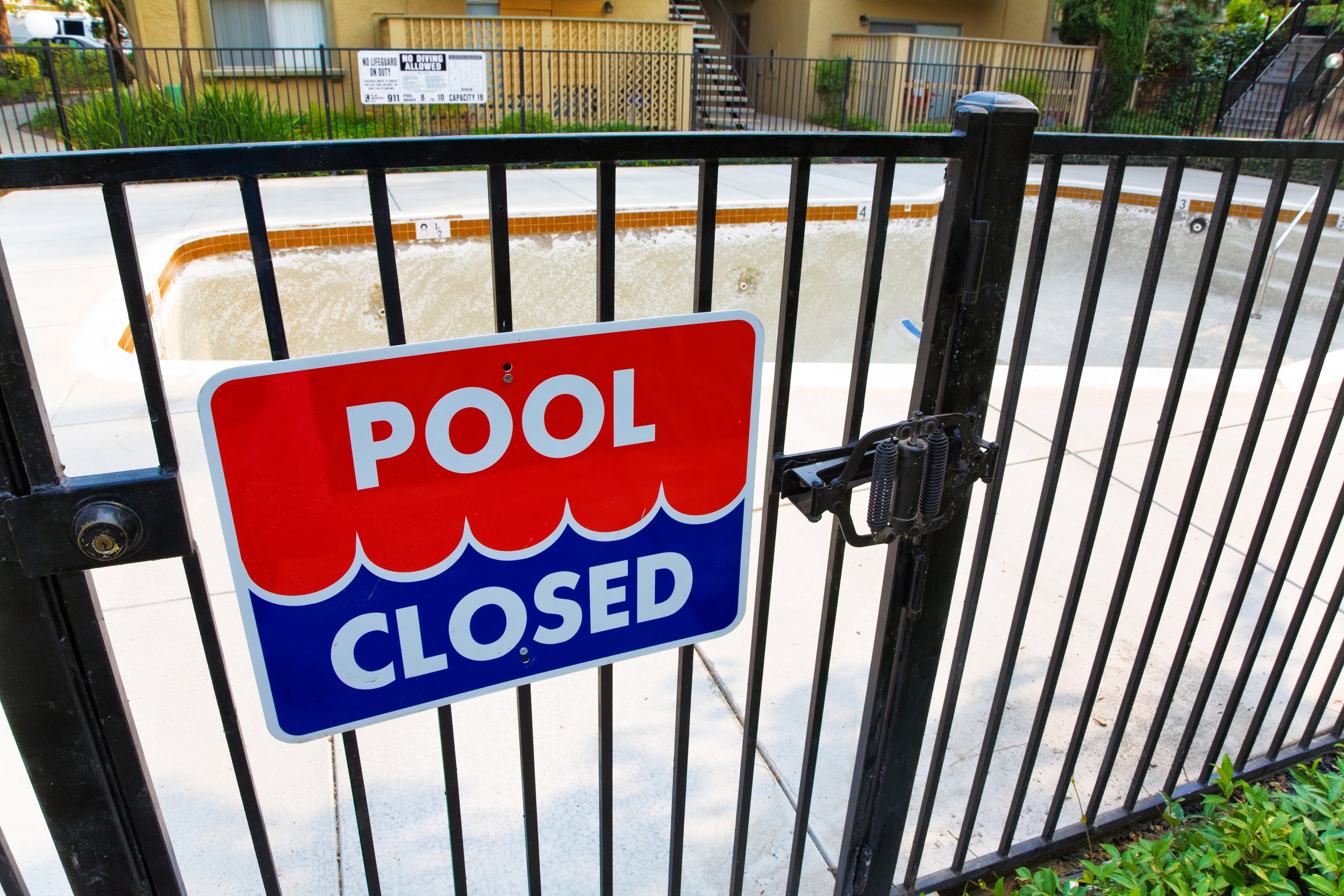 Closed swimming pool with a "Pool Closed" sign on a gate