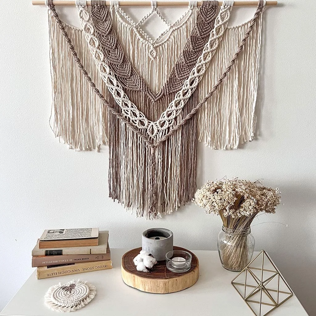 Óriás makramé beige falidísz egy komód fölött száraz virágokkal