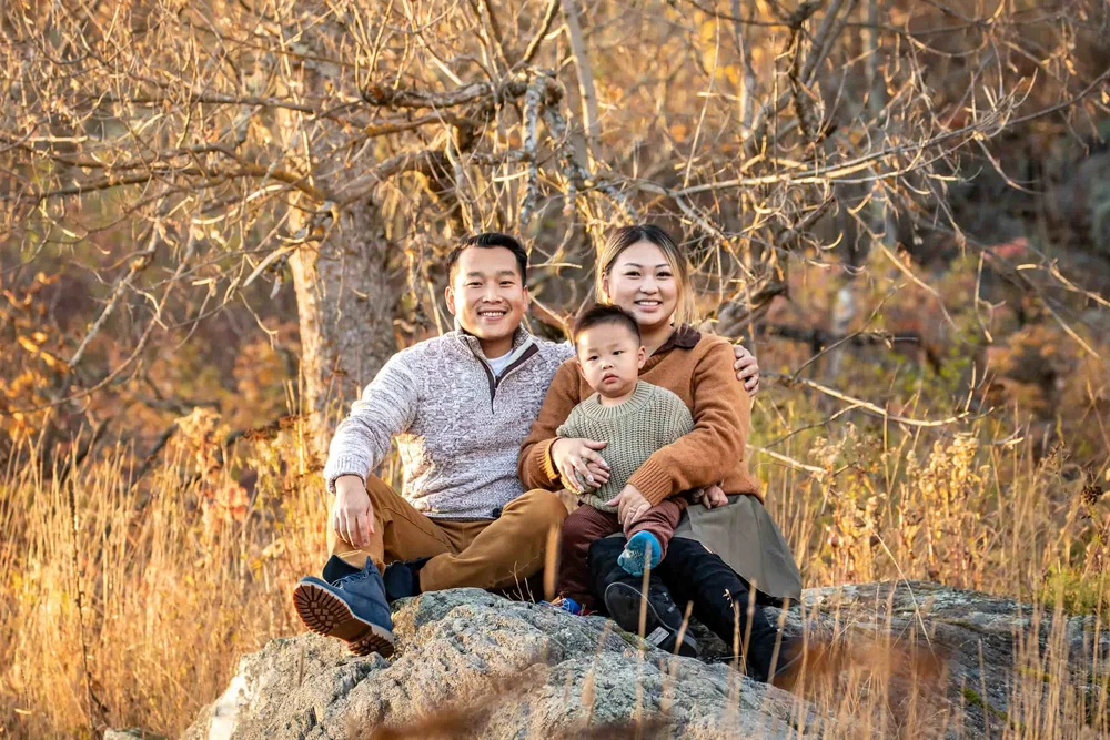 Parents sitting with their young child during a warm outdoor family portrait session