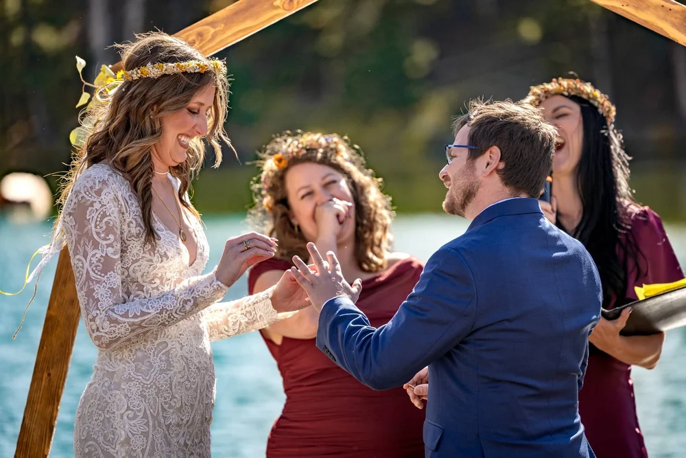 Bride placing a wedding ring on the groom's finger during an intimate outdoor Colorado ceremony