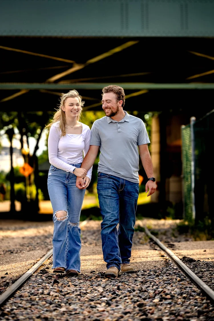 Couple walking hand in hand along railroad tracks during a candid outdoor portrait session