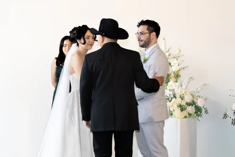 Bride and groom greeting a man in a black cowboy hat at the front of their Longmont wedding ceremony
