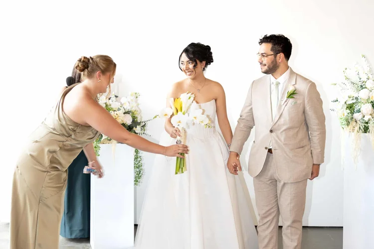 Wedding attendant handing a bouquet to the bride beside the groom in Longmont, Colorado