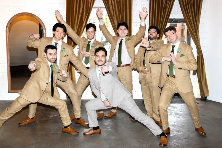 Groom and groomsmen striking playful poses indoors at a Longmont, Colorado wedding
