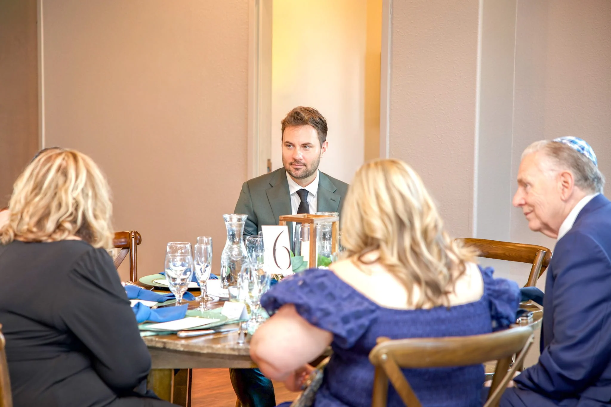 Guests engaged in conversation around a table during a formal event in Colorado, photographed by Grayson Flicks Photography.