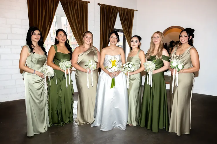 Bride holding a bouquet beside bridesmaids in shades of green at her Longmont, Colorado wedding