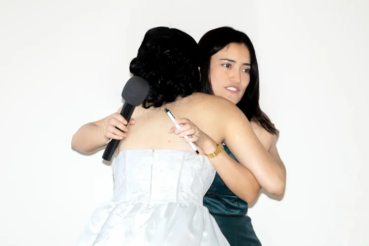 Bride embracing a woman holding a microphone at her Longmont, Colorado wedding reception