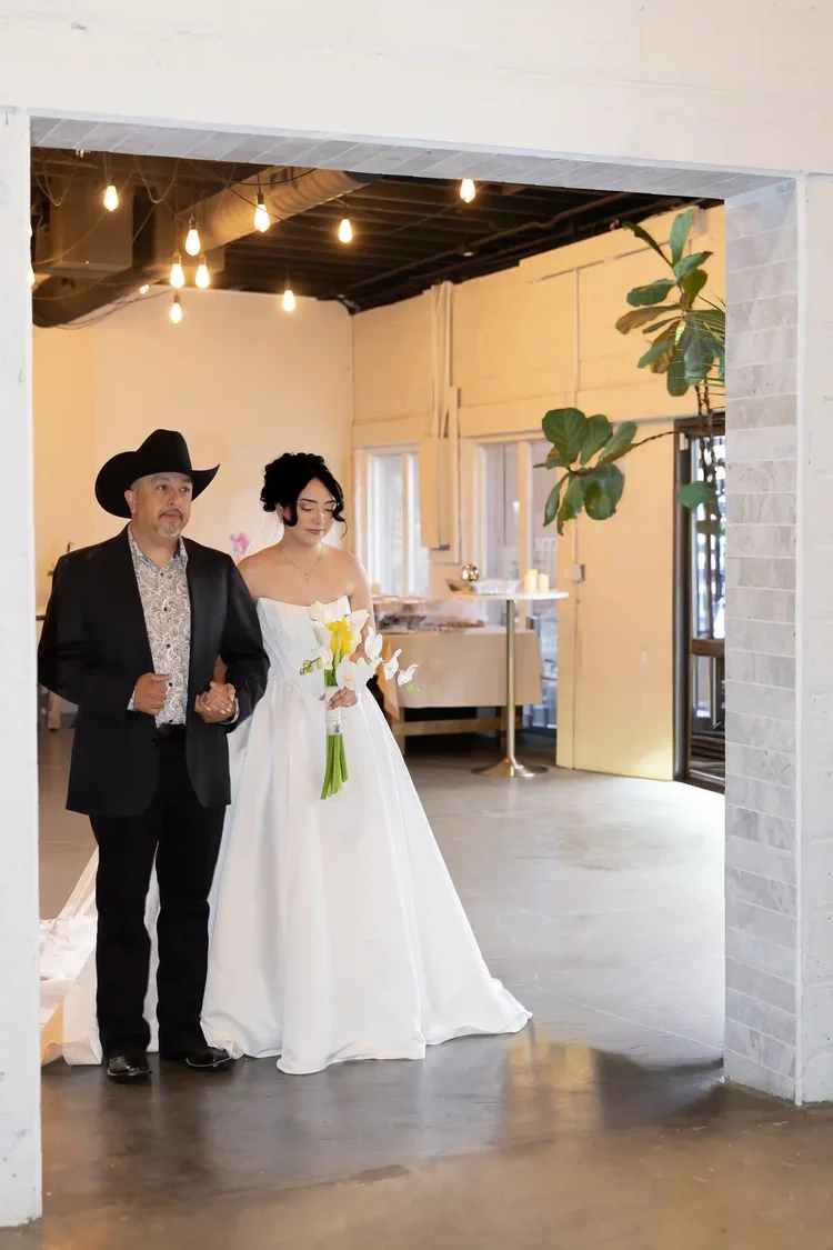 Bride entering the wedding ceremony beside a man wearing a black cowboy hat in Longmont, Colorado