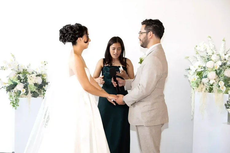 Bride and groom holding hands in front of the officiant at their Longmont, Colorado wedding ceremony