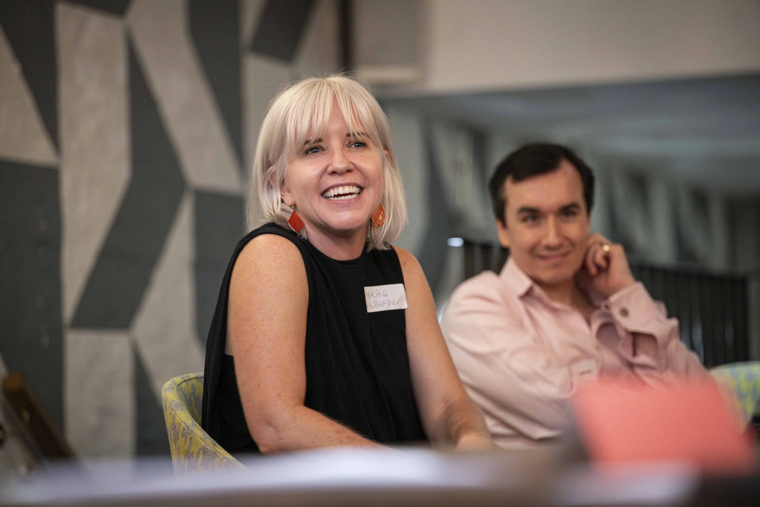 A girl wearing black sleeveless smiling while speaking during an On Sale Live Lates networking discussion with attendees.