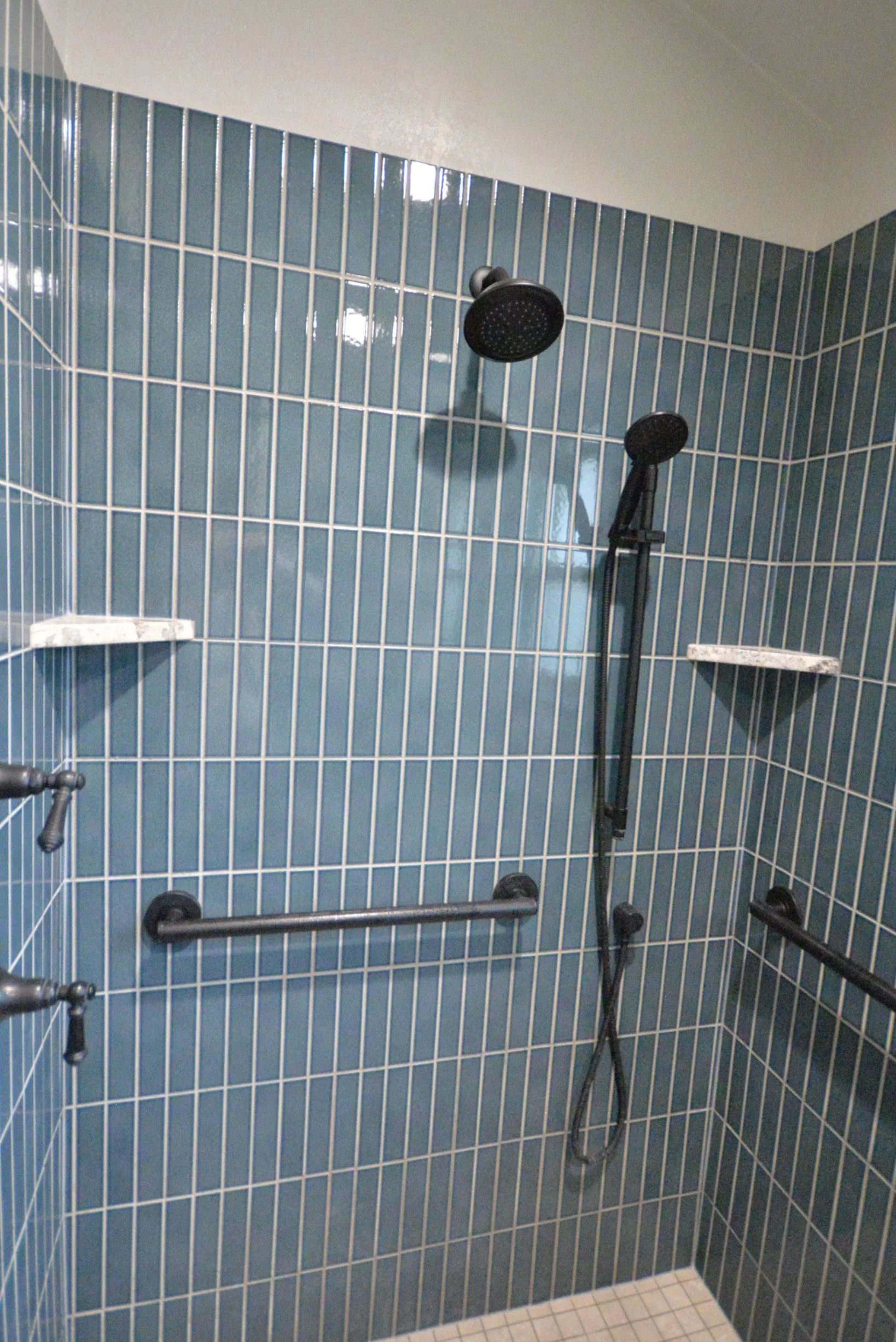 Blue vertical subway tile shower with oil rubbed bronze shower fixtures. 