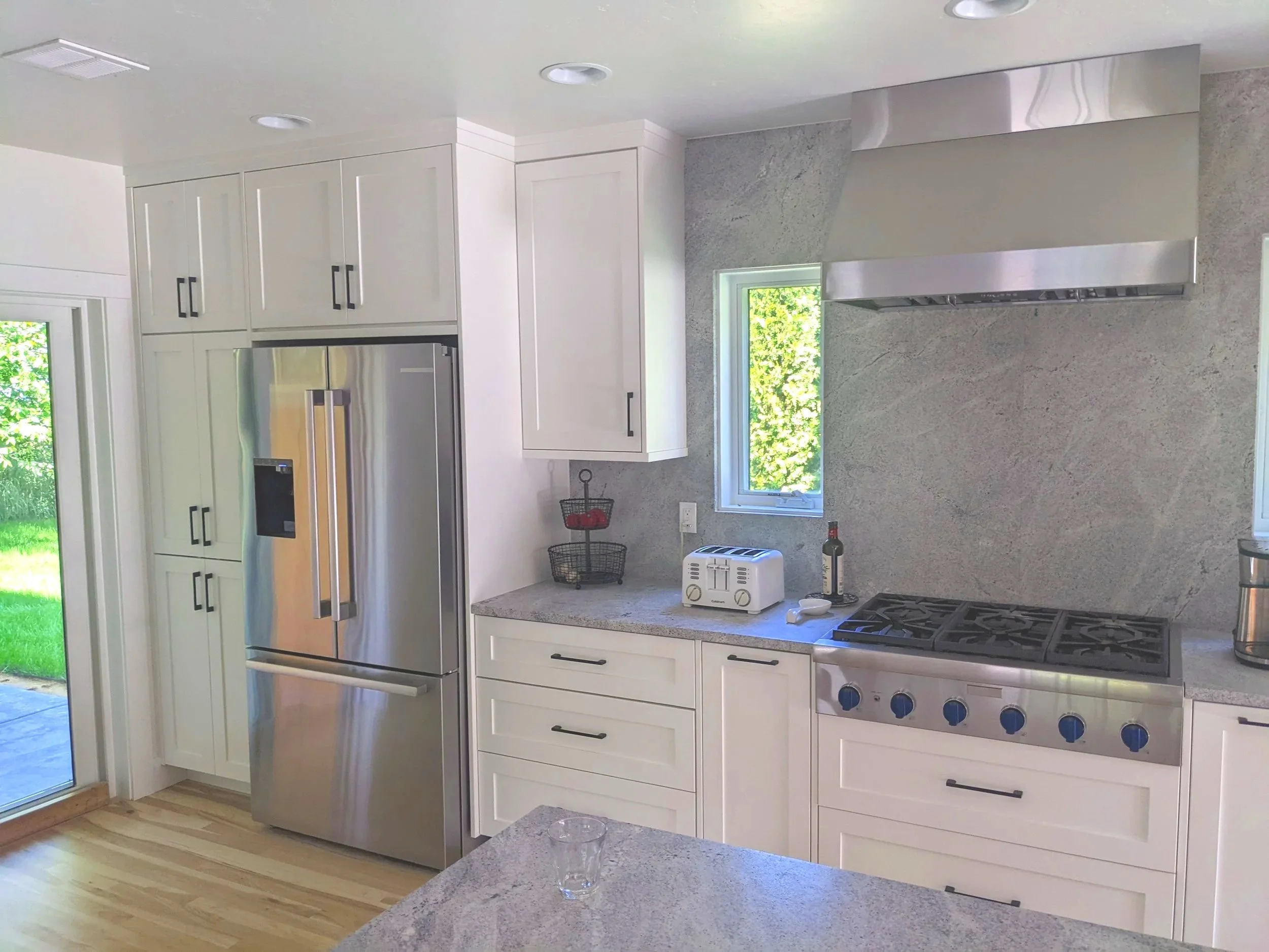 Kitchen with white cabinets and granite full height quartz backsplash.
