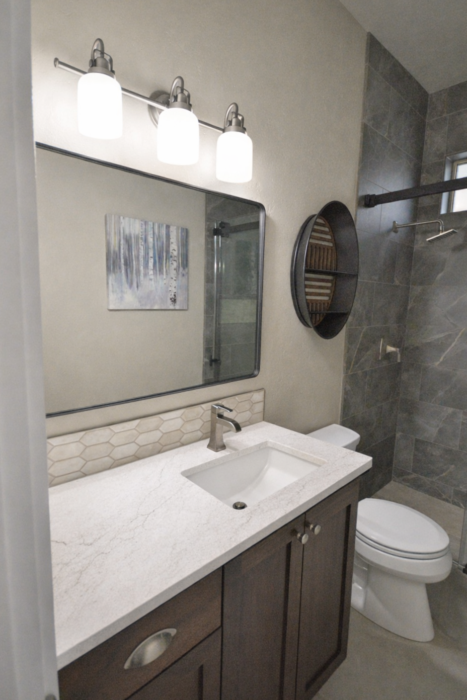 Light quartz countertop on dark stained cabinet. Large tile to ceiling in shower.