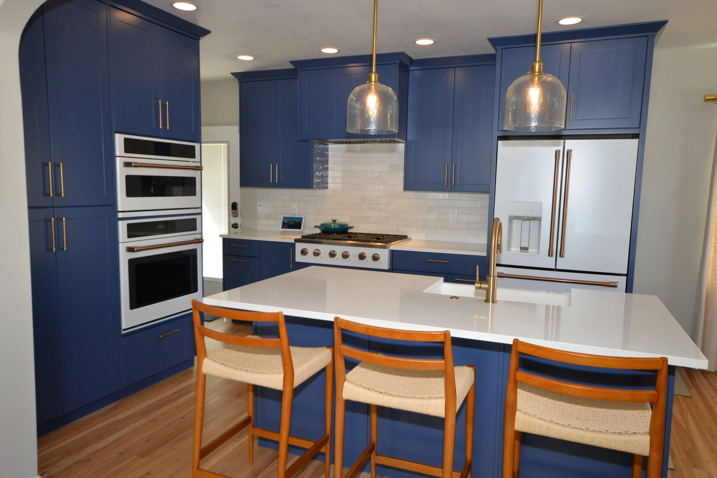 Small kitchen with blue cabinets and white appliances with brushed gold finishes