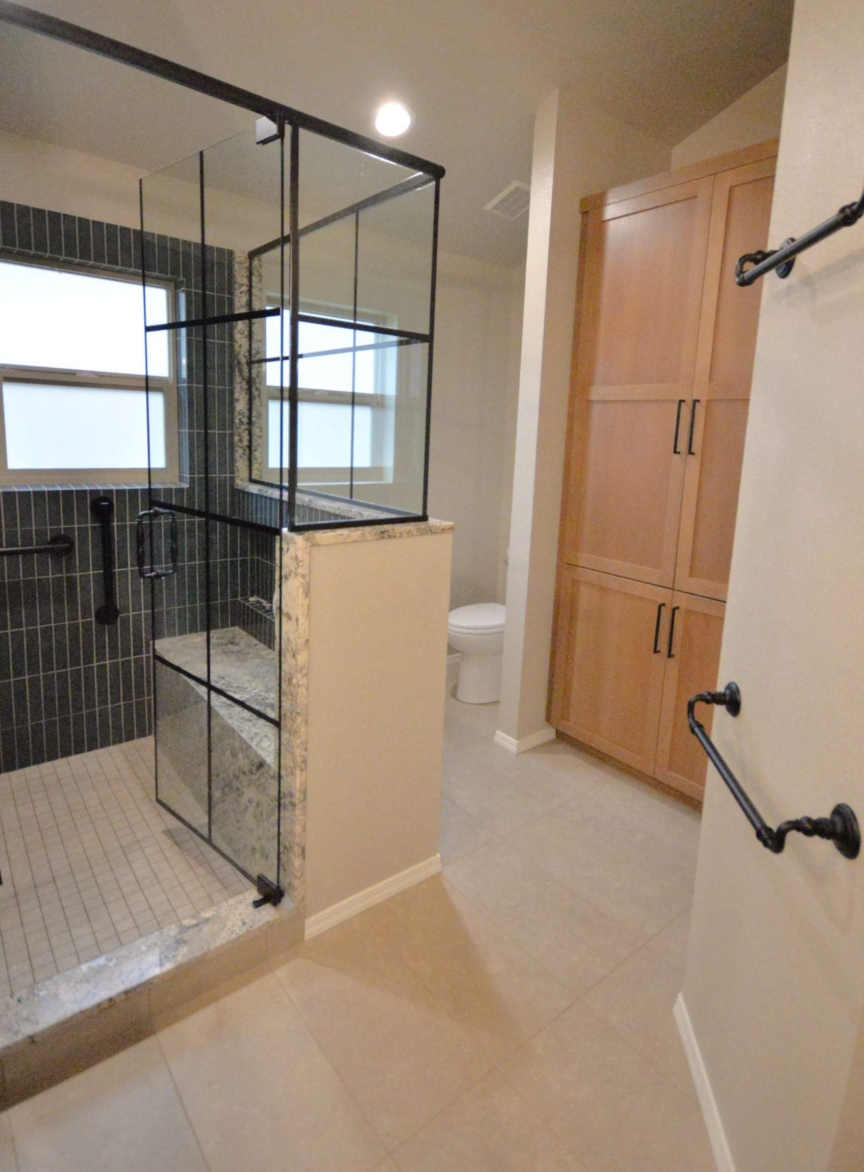 Walk-in shower with paned glass surround on pony walls. 