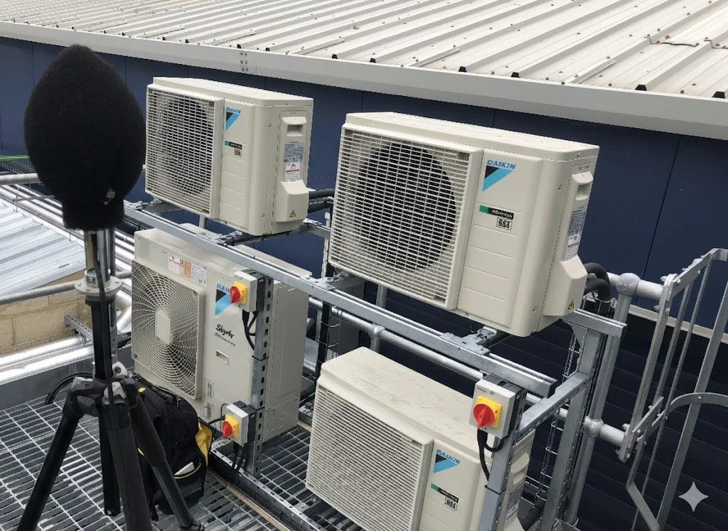Multiple HVAC units installed on a rooftop, with a microphone on a stand in the foreground.