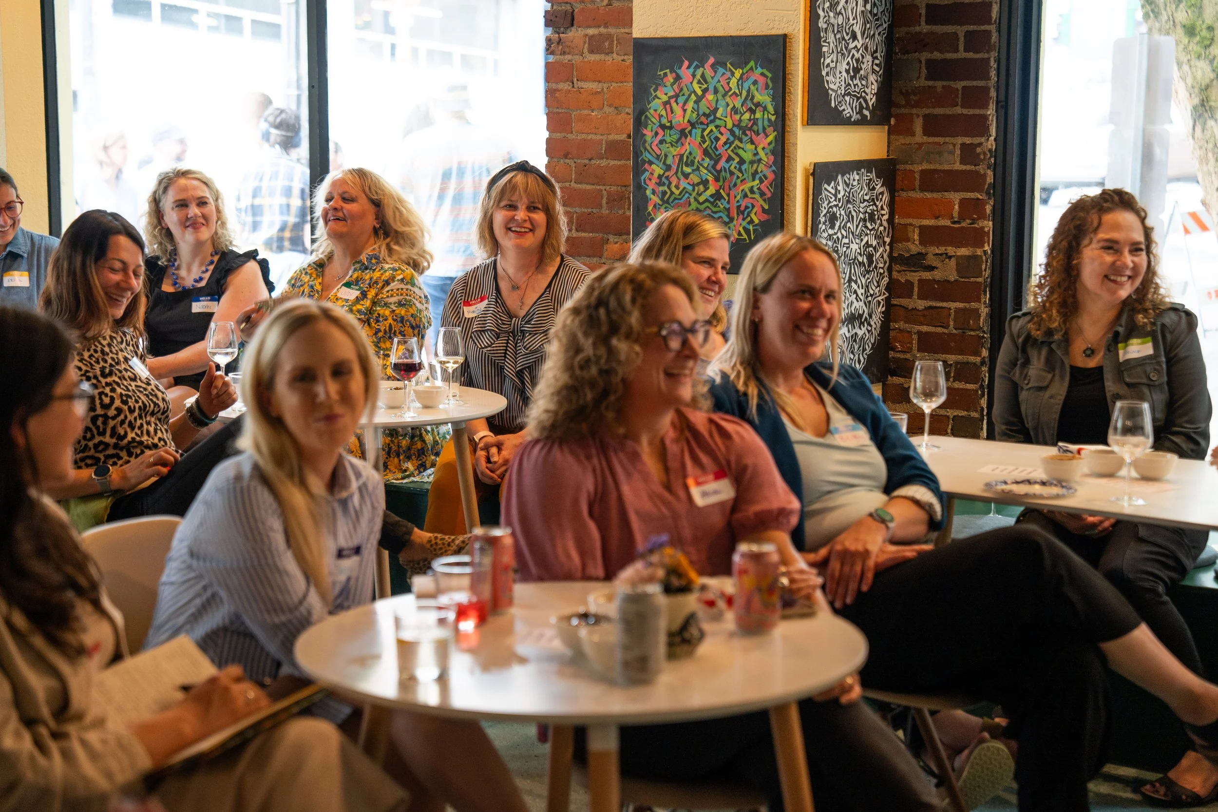 Women in front of windows and a brick wall laughing.