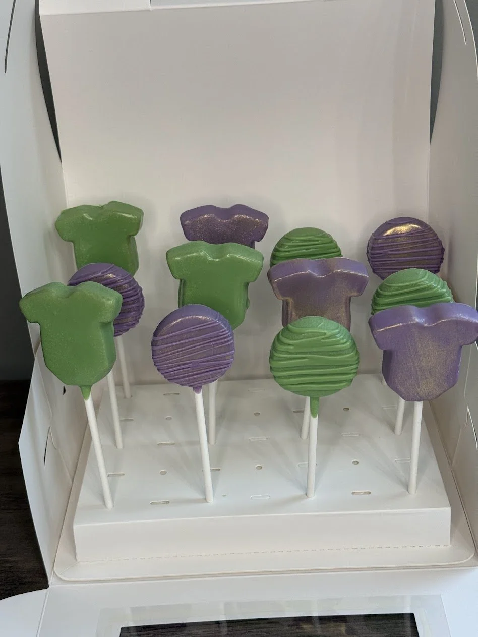 Decorative lollipops in purple and green colors arranged in a display box.