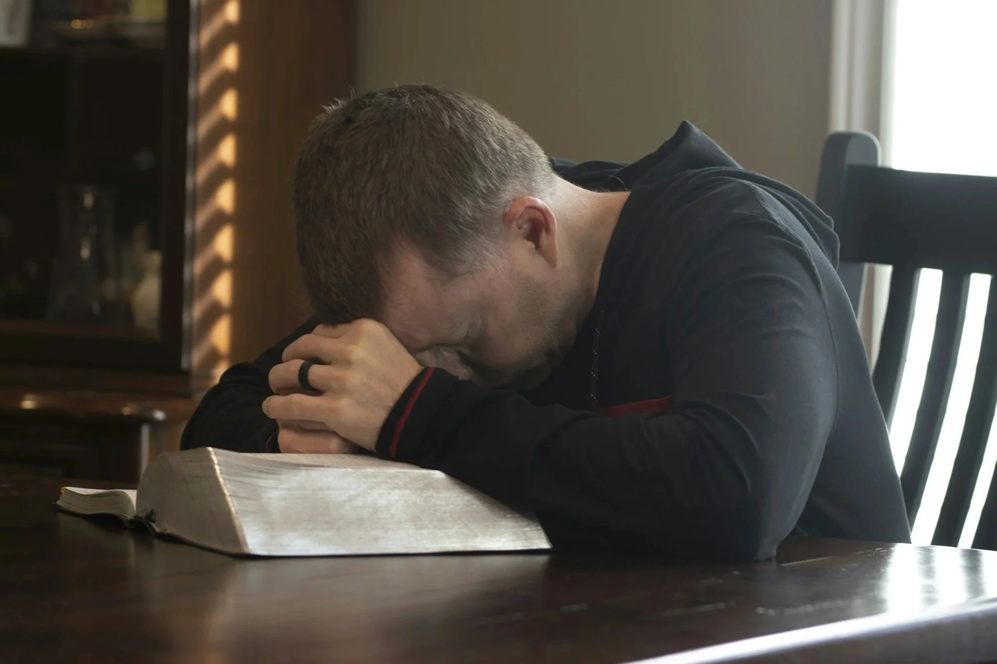Pastor praying with an open Bible while reflecting on stewardship and financial decisions in ministry.