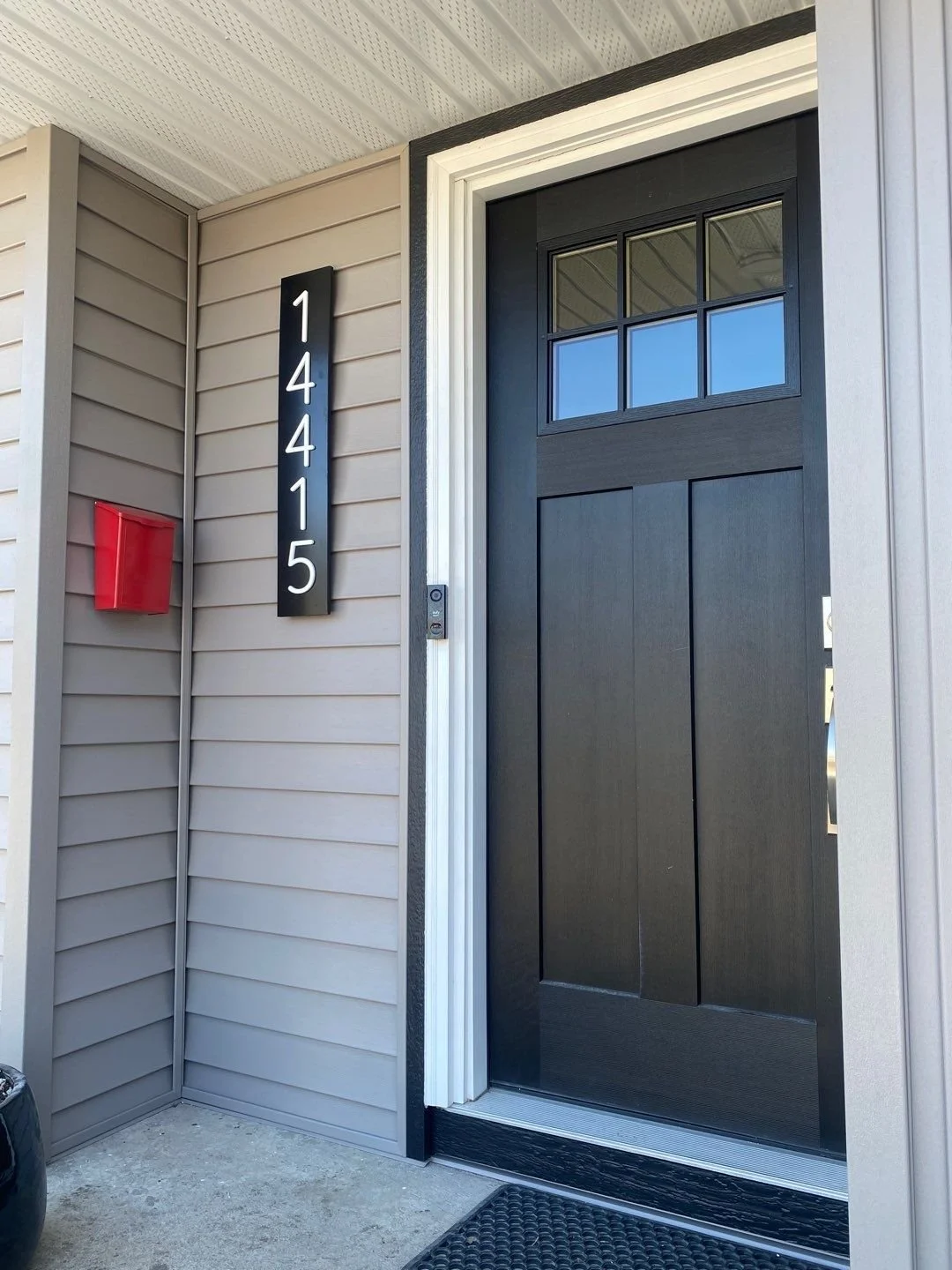 Front entry of a home in Edmonton featuring vinyl siding in Harvard Slate, a cute red mailbox, and striking house numbers.