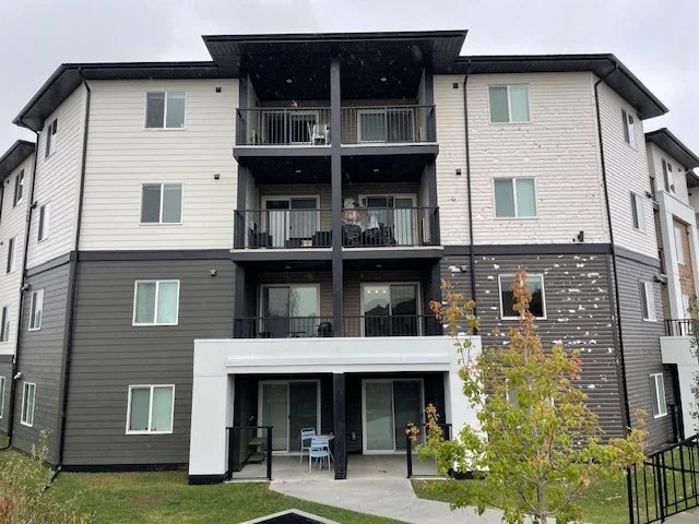 Picture showing the impact of hail on Hardie siding compared to vinyl siding on the same Edmonton area condo building.