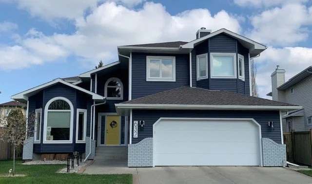 Two storey home in Edmonton with navy blue vinyl siding and yellow door