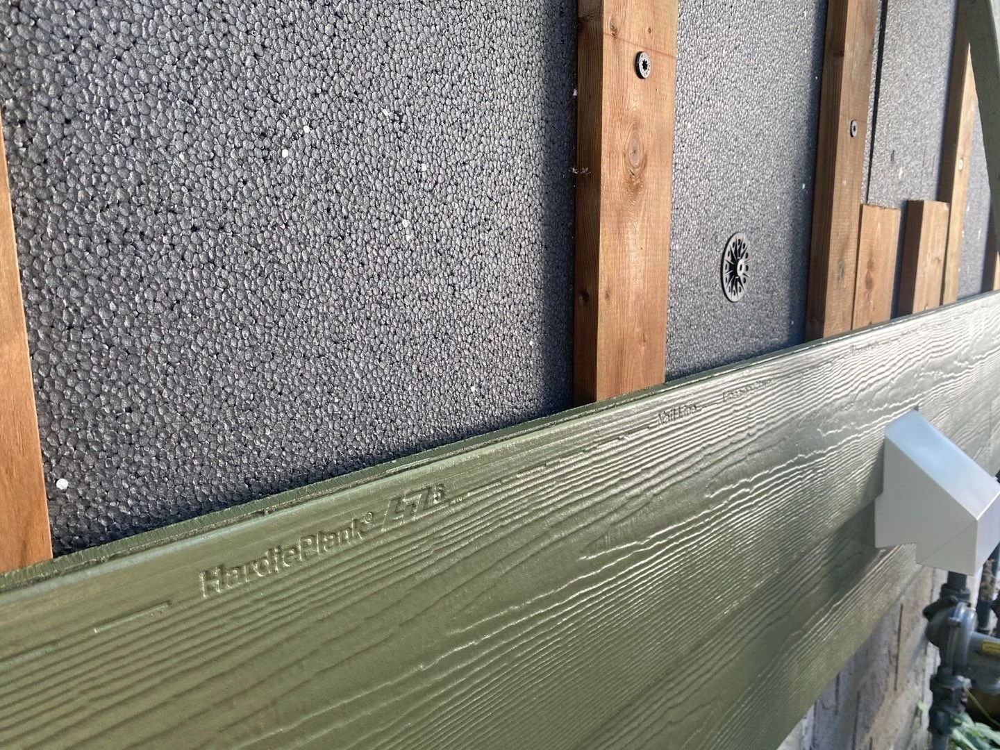 Close Up photo of Hardie Plank being installed over exterior insulation