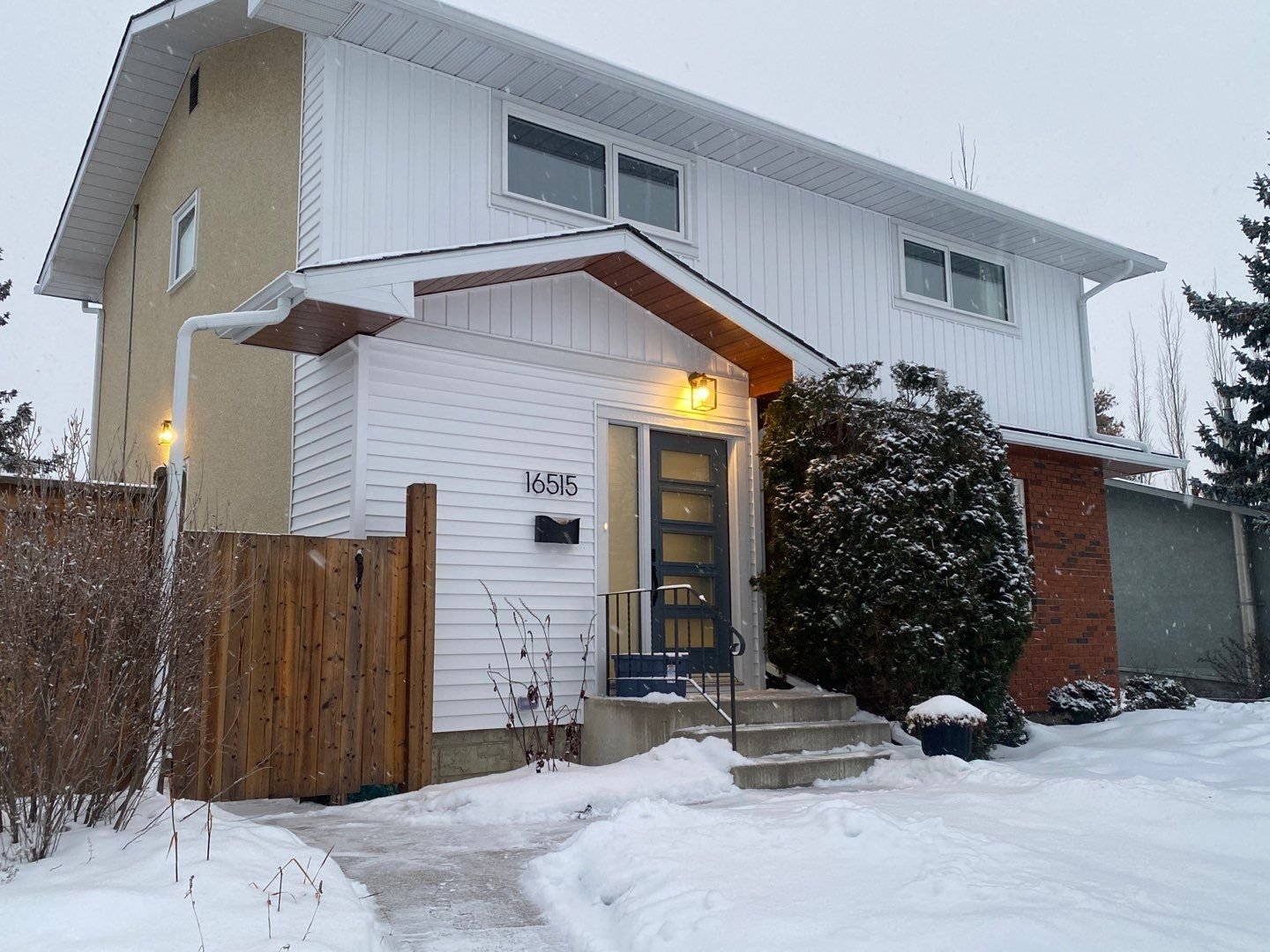 This front facade renovation in west Edmonton includes white vinyl siding, both horizontal and vertical board & batten.