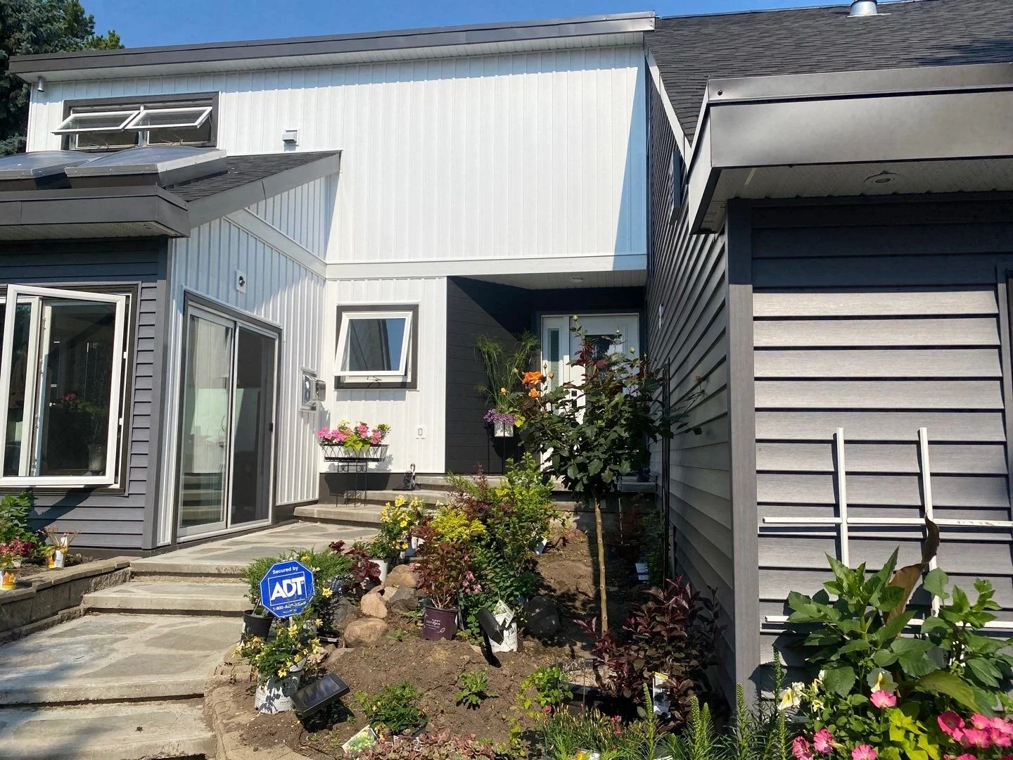 A contemporary exterior renovation featuring vinyl siding and Lux steel V-groove panels.