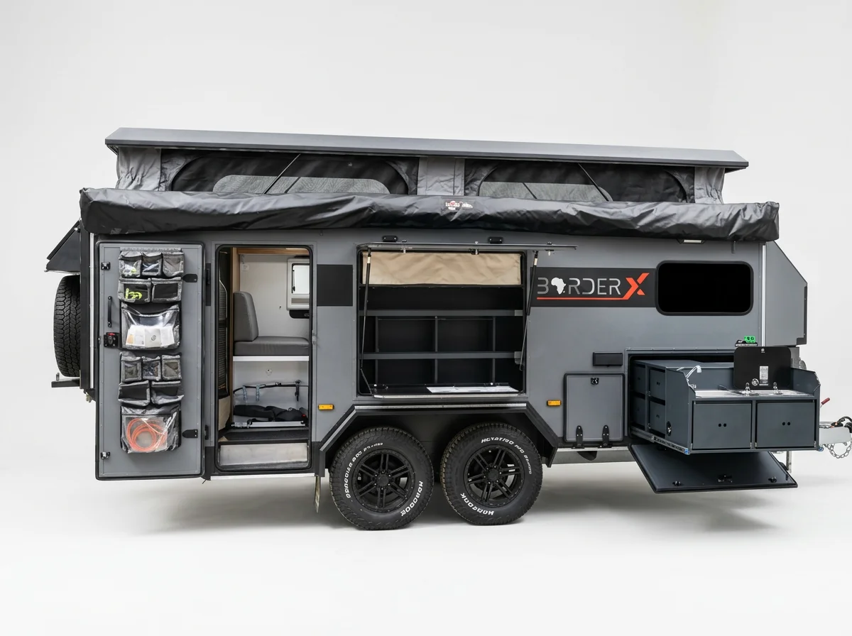 A gray off-road BorderX Extreme with various storage compartments and accessories, including a fold-out awning, spare tire, and a small side fridge.