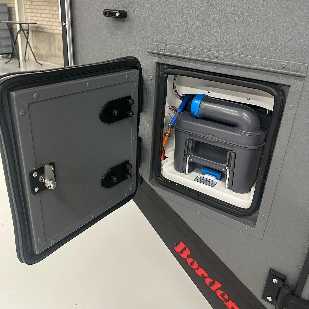Open door of a bounce house showing electronic control panel and wiring inside.