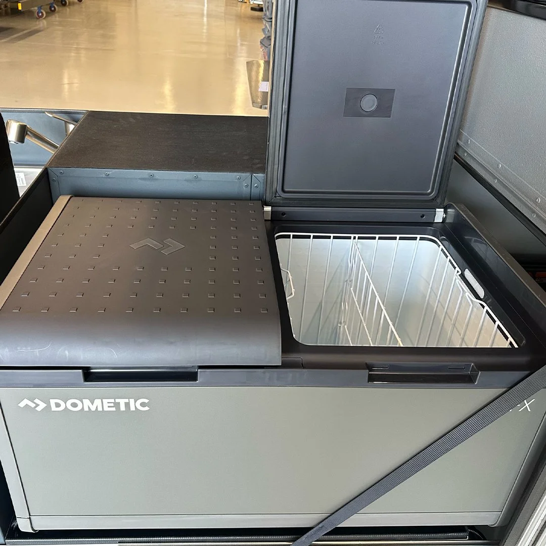 Open Dometic portable freezer with empty interior and lid partially open in a store.