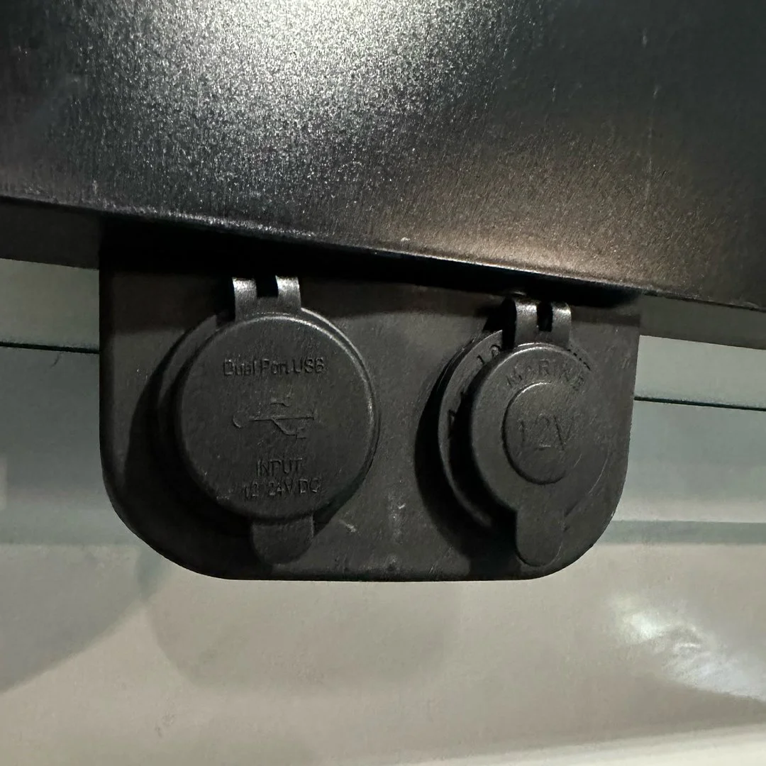 Close-up of two black electrical sockets, one labeled 'DualFuse' with an input of 12-24V DC, the other labeled '12V' on a black surface.