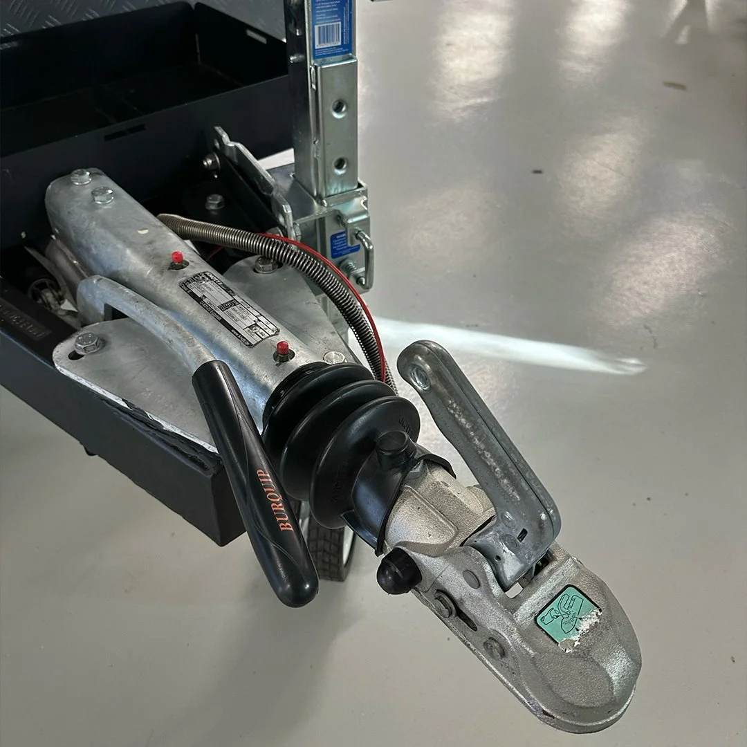 Close-up of a boat trailer's coupler and hitch assembly on a polished concrete floor.